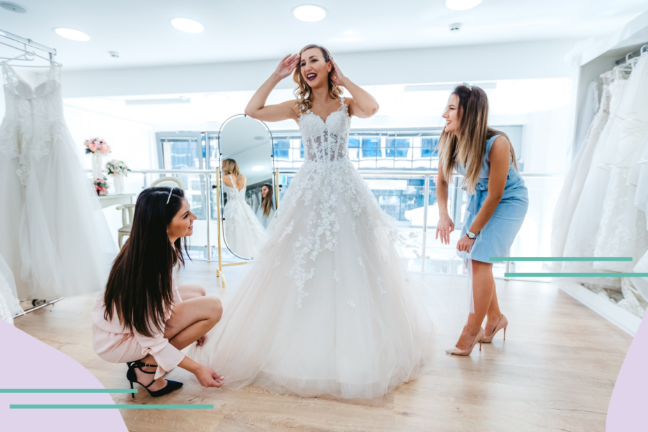 A bride-to-be tries on wedding dresses at a shop with employees help.